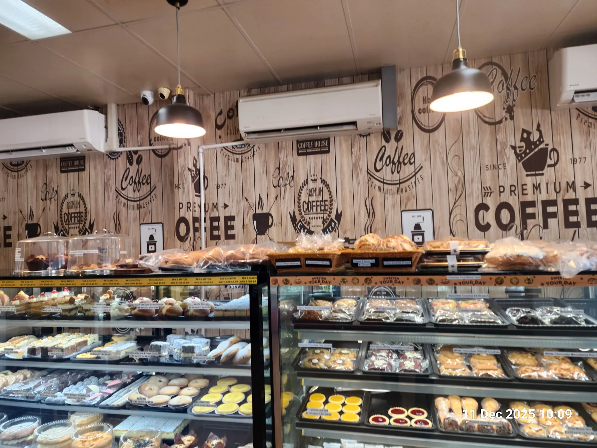 Bakery interior showing full display counters of breads, cakes and pastries with coffee branding wall